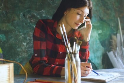 Woman talking on phone while writing in notebook